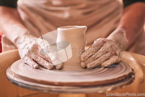 Image of Hands, pottery and clay mold on table for creative art design, product or sculpture for startup workshop. Hand of crafty artist molding ceramic material in creation, shape or tool with spinning wheel