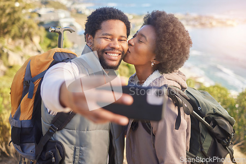 Image of Selfie, kiss and black couple hiking on mountain for fitness, fun and romantic walk in natural landscape. Romance, man and woman taking self portrait in nature with smile in mountains on island trip