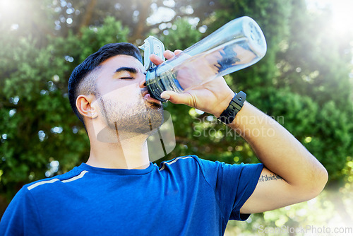 Image of Nature, drink and runner with water in bottle, relax for thirst on fitness workout in park. Health, exercise and freedom, man drinking in forest while on marathon training run in jungle in Brazil.