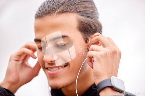 Image of Closeup, fitness and outdoor with earphones, motivation and workout for wellness, healthy lifestyle and music. Zoom, male and athlete with headphones, smile and podcast with exercise and determined