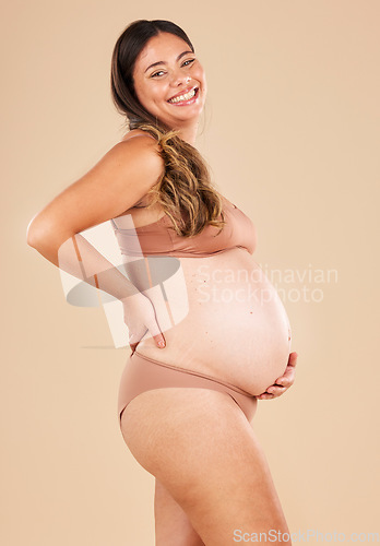 Image of Portrait, pregnant and stomach with a model woman in studio on a beige background for motherhood. Baby, beauty and wellness with an attractive young mother in underwear for pregnancy or body health