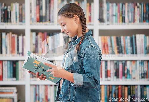 Image of Books, education or child in a library reading for knowledge or development for future growth. Scholarship, girl or school student with a happy smile studying or learning information in a fun story