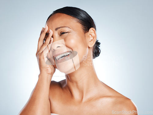 Image of Laughing, hand and woman in studio for skincare, hygiene and grooming against grey background. Beauty, joy and Mexican lady model relax with wellness, routine and skin treatment, posing and isolated