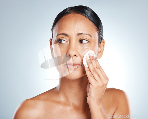 Image of Face, beauty and woman with cotton in studio for cleaning, wellness and grooming on grey background. Facial, clean and girl with pad for toner, skincare and moisturizing skin while posing isolated