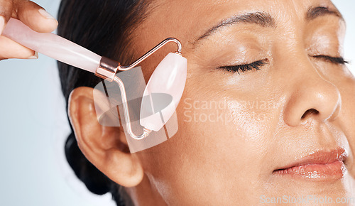 Image of Face, mature woman with roller and massage closeup, antiaging skincare with beauty isolated on studio background. Facial, cosmetic tools and dermatology with natural cosmetics and skin wellness