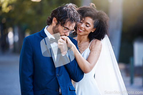 Image of Wedding, happy couple and kiss on hand at marriage celebration event together with commitment. Interracial man and woman at ceremony with trust, partnership and care while outdoor with flower bouquet