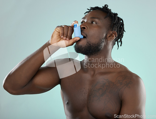 Image of Asthma pump, sick and man in a studio with bronchitis, illness or medical chest problems. Inhaler, healthcare and African male doing a asma treatment with medication isolated by a blue background.