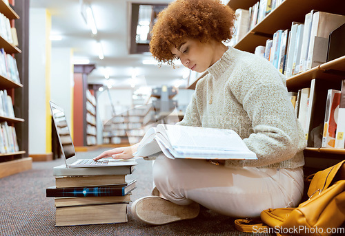 Image of College learning, library and book reading with laptop of a black woman student on the ground. Education research, bookshelf and books of a young female looking studying for a school test or exam