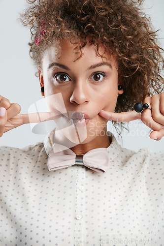 Image of Silly, goofy and portrait of woman in studio with fingers in her cheeks for funny face expression. Fashion, funky and female model with a edgy and stylish bow tie outfit isolated by white background.