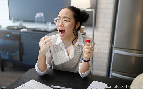 Image of Covid test, mouth and pcr exam with Asian woman medical and healthcare testing with cotton swab. Disease, virus and health check of a young person in a home kitchen looking for corona results