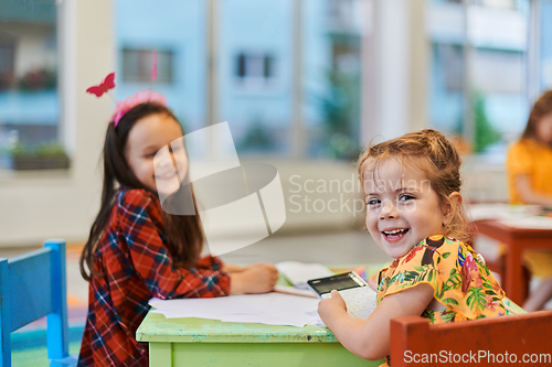 Image of Creative kids during an art class in a daycare center or elementary school classroom drawing with female teacher.