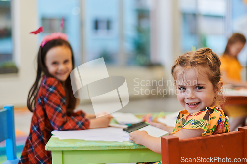 Image of Creative kids during an art class in a daycare center or elementary school classroom drawing with female teacher.