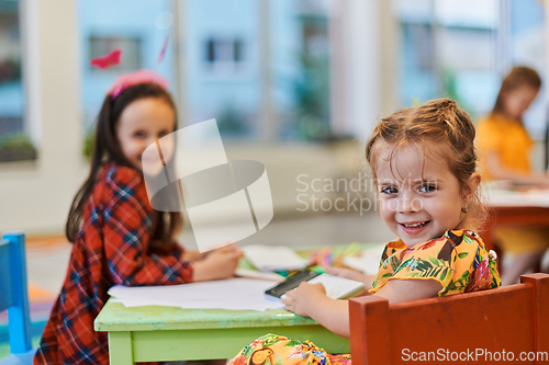 Image of Creative kids during an art class in a daycare center or elementary school classroom drawing with female teacher.