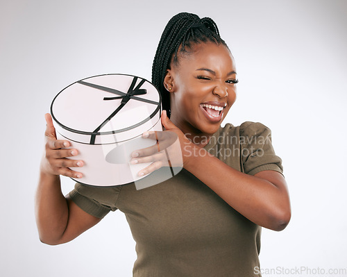 Image of Box, present and portrait of black woman on studio background. Happy female, present and package with wink for birthday, excited celebration and promotion to celebrate happiness, giveaway and smile