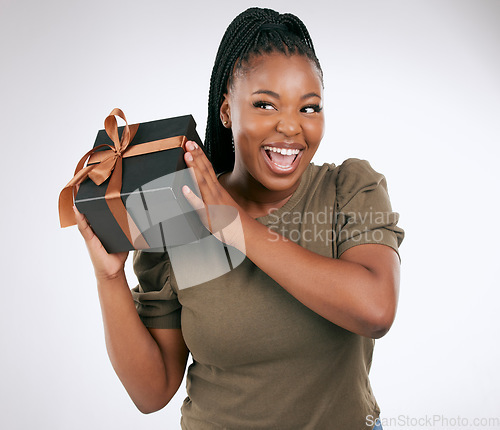 Image of Gift, box and woman guess in studio with package, smile and celebration. Happy, curious and black female with present, surprise and ribbon on background, birthday and giveaway of product promotion