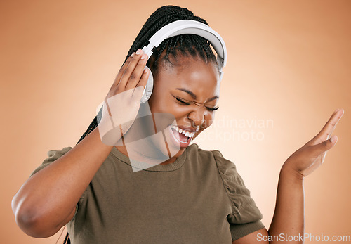 Image of Headphones, singing and black woman isolated on studio background for mental health, energy and radio music. Singer, voice and gen z african person listening to audio technology with mockup space