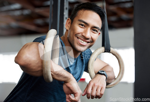 Image of Portrait, gymnastic rings and olympics with a man gymnast hanging on equipment for workout in gym. Face, fitness and exercise with a male athlete training in gymnastics for health or power