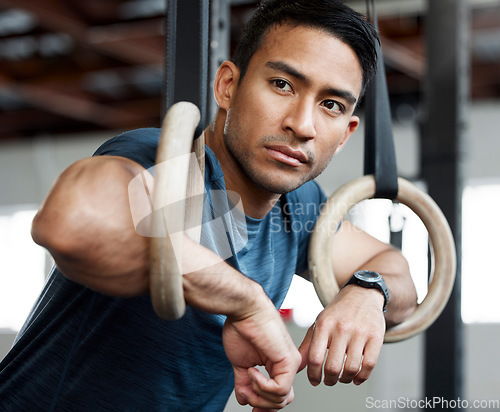 Image of Thinking, gymnastic rings and olympics with a man gymnast hanging on equipment for workout in gym. Idea, fitness and exercise with a male athlete training in gymnastics for health or power