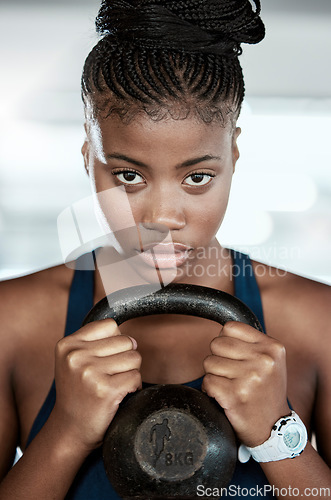 Image of Fitness, portrait or black woman in gym with a kettlebell for strength training, exercise or workout. Motivation, face or healthy strong athlete with focus or weight for muscle development or growth