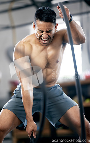 Image of Fitness, battle ropes or strong man training for body goals in painful workout or exercise at a sports gym. Resilience, mindset or healthy athlete with biceps power, motivation or focus exercising