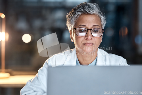 Image of Woman, doctor and laptop in office at night at workplace, hospital or desk for medical career vision. Healthcare expert, dark clinic or focus for reading at computer, email or cancer research article