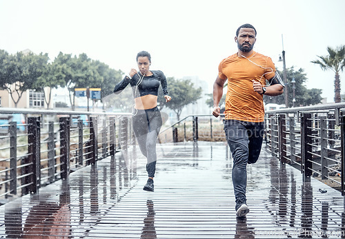 Image of Personal trainer, rain and athletes running as exercise on a city bridge training, fitness or workout outdoors in town. People or fit friends sprint fast for wellness, cardio and health lifestyle