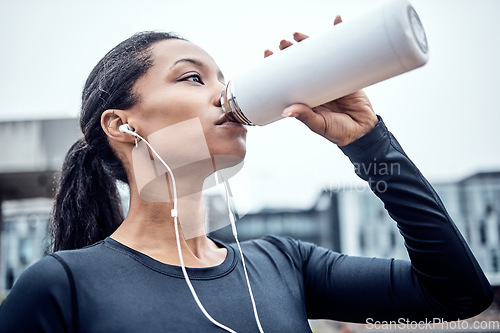 Image of Fitness, water and black woman drinking in city for wellness, healthy body and cardio workout outdoors. Sports, motivation and girl listening to music for exercise, running and marathon training