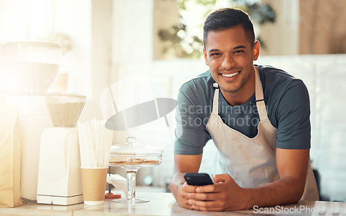 Image of Barista, portrait and man with smartphone, smile and search online on break, connection and social media. Male employee, guy and worker in cafe, behind counter and cellphone for communication or text