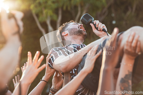 Image of Crowd, surfing and man singing at party, outdoor music festival or social gathering. Microphone, energy and male singer diving in audience group at performance event, celebration or crazy fun weekend