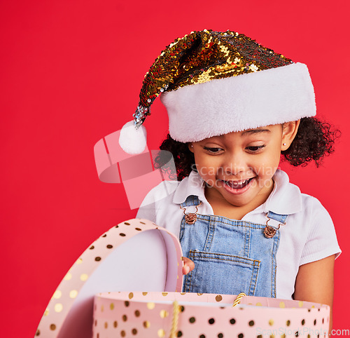 Image of Wow, christmas and gift with a black girl on a red background in studio for festive celebration or surprise. Box, present or kids with a happy female child celebrating a holiday tradition in december