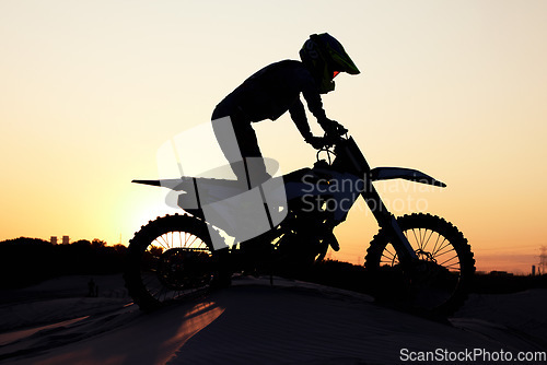 Image of Silhouette, sports and motorcycle riding against sunset, sky and background in nature, extreme sport and adrenaline. Biking, motorbike and person driving on dirt road, sunrise and shadow or freedom