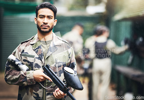 Image of Portrait, paintball and camouflage with a sports man holding a gun for a game or competition. Fitness, exercise and serious with a male athlete carrying a weapon or marker for military training