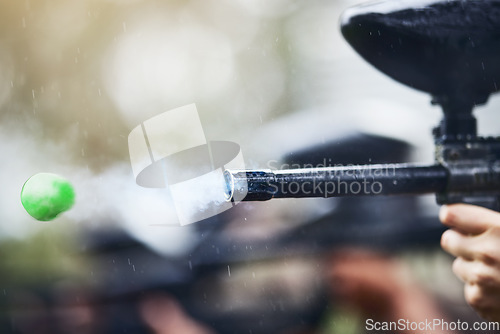 Image of Gun, paintball and ball closeup with person shooting for fun, extreme and sport, fitness and training. Zoom, paintball marker, and hand, practice and game with people competing, speed and power