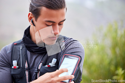 Image of Fitness, phone and man hiking outdoor, trekking in nature with earpods, music and workout with exercise app. Health, wellness and body training with mockup, athlete listen to podcast with 5g on hike