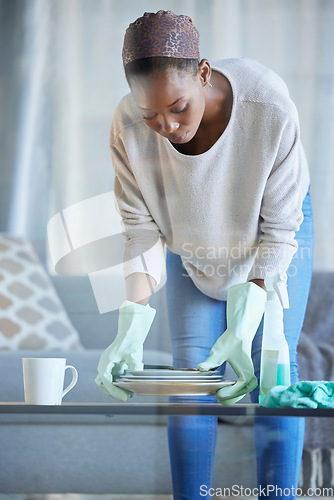 Image of Black woman, cleaner and home spring cleaning of a professional maid holding dirty dishes. Working, housekeeper and focus of a female in a living room helping with chores and housework in a lounge