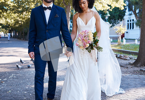 Image of Love, wedding and couple with flowers holding hands outdoors at park together. Marriage, diversity or affection, care or romance of man, woman or bride and groom walking with bouquet of roses.