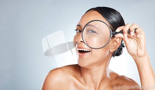 Image of Magnifying glass, beauty and woman in a studio with a skincare, health and natural face routine. Eye, search and portrait of a mature female with wrinkles for a wellness anti aging facial treatment.