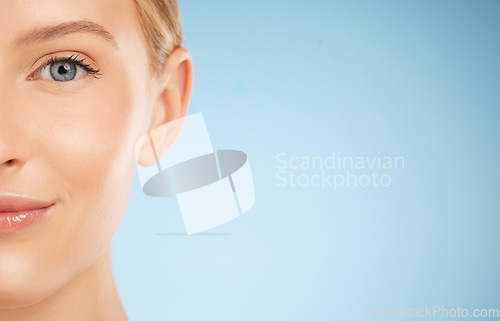 Image of Skincare, smile and half portrait of a woman for dermatology isolated on a blue background. Makeup, wellness and face of a model for cosmetics, health and collagen with mockup space on a backdrop