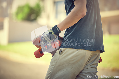 Image of Fun, skateboard and man skateboarding in a neighborhood for fitness, exercise and training. Sport, cardio and hands of a teenager with a board in the street to travel, commute and playing in the road