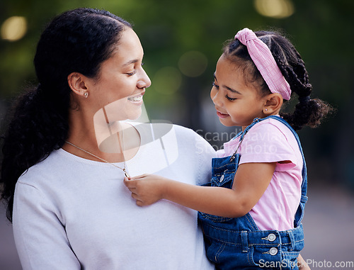 Image of Family, mother and carrying little girl with smile for outdoor bonding and hugging at a park. Motherhood support, care and love with daughter, child or kid touching necklace or jewelry on mom outside