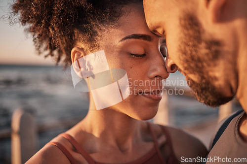 Image of Black couple, hug and touching forehead embracing relationship, compassion or love and care by the beach. Happy man and woman with heads together smiling in happiness for support, trust or romance