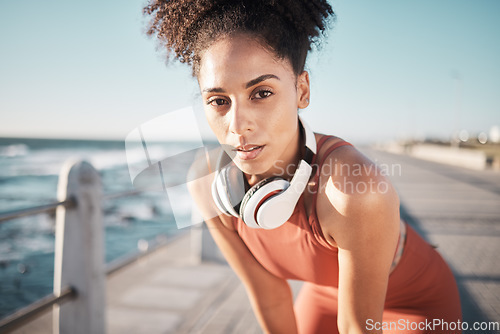 Image of Portrait, fitness and tired with a black woman runner on the promenade for cardio or endurance exercise. Running, workout or breathing with a young female athlete training outdoor by the sea