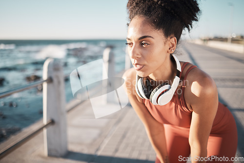 Image of Thinking, fitness and breathing with a black woman runner on the promenade for cardio or endurance exercise. Running, workout or health with a young female athlete training outdoor by the sea