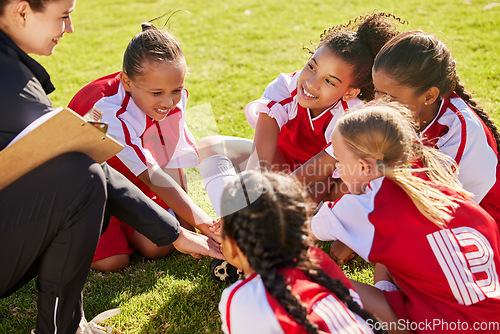 Image of Girl soccer group, sitting and planning with coach on field with smile, team building or motivation at training. Female kids, sports diversity or happy with friends, teamwork or strategy for football