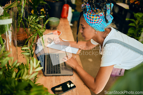 Image of Laptop, small business or black woman writing a checklist on plants or flowers for commerce or stock inventory. Management, store manager or entrepreneur planning or working on floral growth research