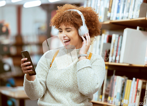 Image of Black woman, phone and music in library with headphones, streaming and laugh for meme on web app. University student, funny blog or social media with smile, smartphone and learning for education goal