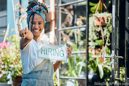 Image of Small business, manager or black woman with a hiring sign at door entrance in floral retail store. Advertising, marketing and happy entrepreneur smiles pointing with job offer message at flower shop