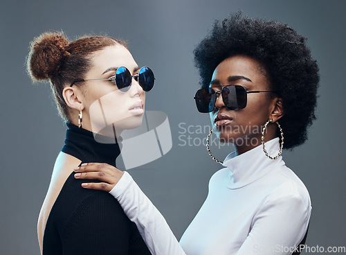 Image of Fashion, friends and women with sunglasses in studio for cosmetics, makeup and futuristic style. Luxury models, designer brand and confident girls with stylish accessory, trendy clothes and jewellery