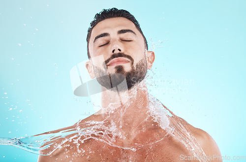 Image of Water, splash and skincare with face of man for shower, self care and natural cosmetics. Luxury, hydration and refreshing with model for dermatology, wellness and cleaning in blue background studio