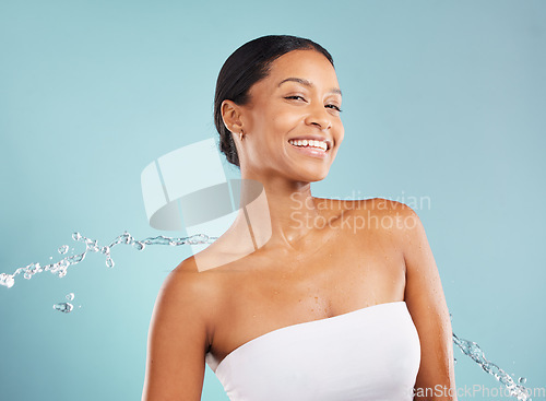 Image of Water splash, black woman and beauty portrait in studio for cleaning cosmetics on blue background. Face of happy female model, shower drops and healthy skincare for body wellness, aesthetic and smile